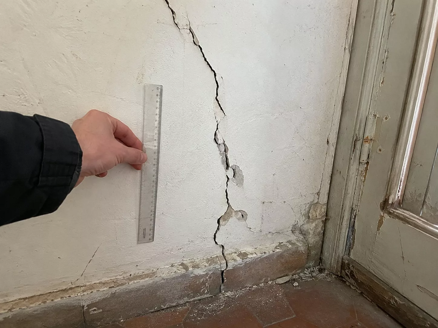 Fissure importante dans le mur d’une maison ancienne avec règle de mesure lors d’un diagnostic sur site.