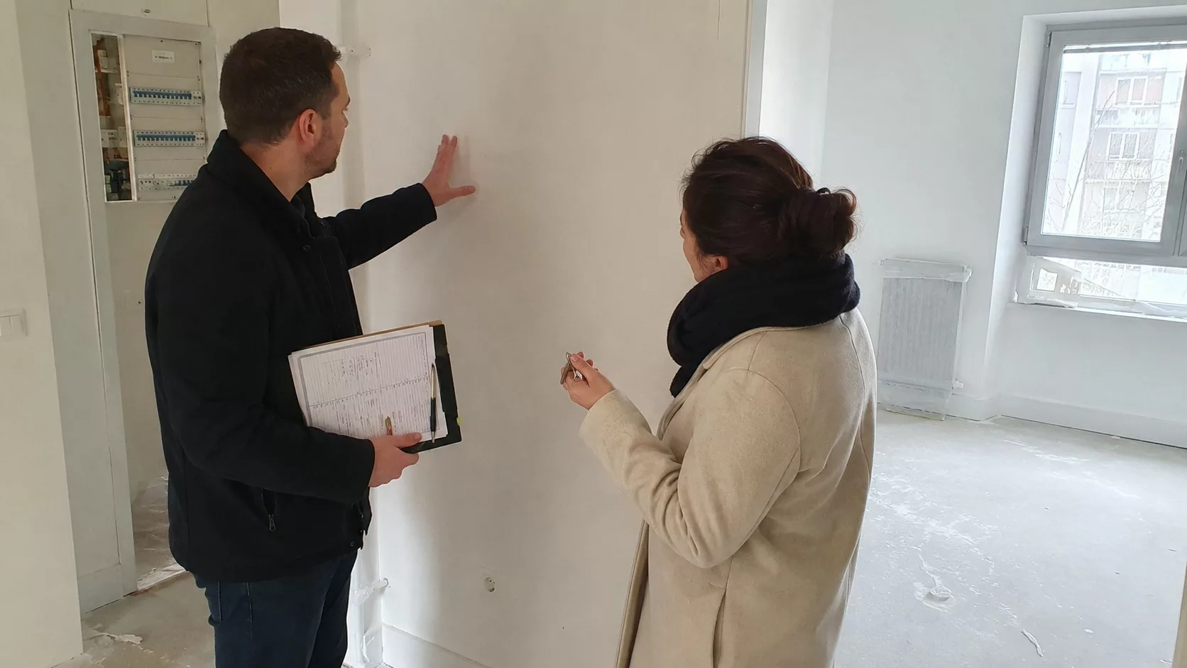 Expert en bâtiment réalisant une inspection de livraison VEFA dans un appartement neuf avec acquéreur, checklist, clés et réserves à vérifier avant remise des clés.