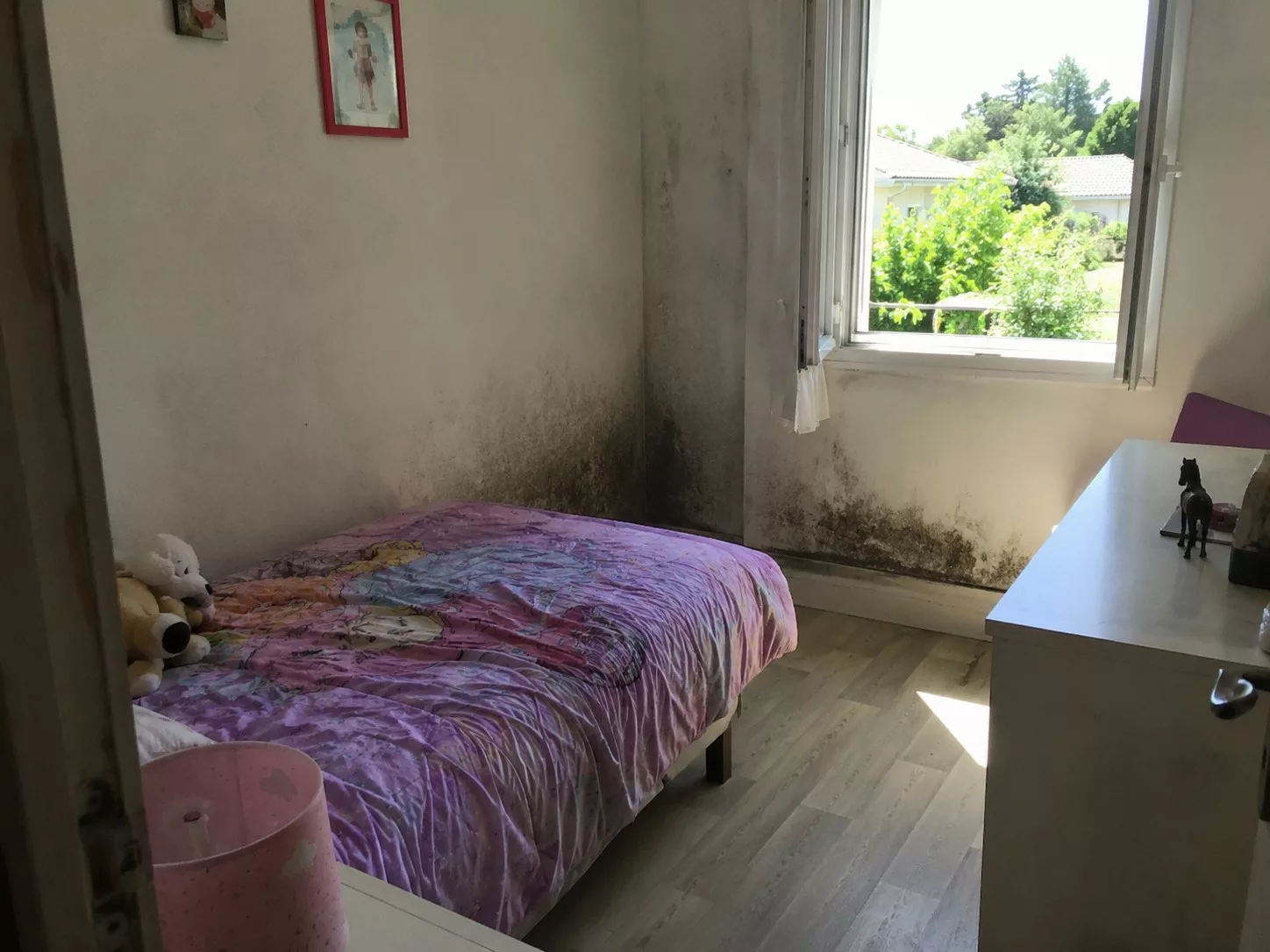 Chambre d'enfant avec moisissures sur le mur près de la fenêtre dans une maison ancienne, illustrant le risque sanitaire de l'humidité