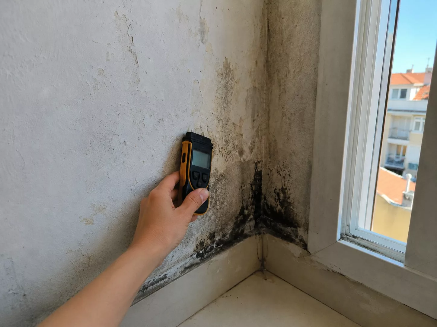 Experte en bâtiment Score Expertises mesurant le taux d'humidité sur un mur intérieur lors d'un diagnostic en Île-de-France