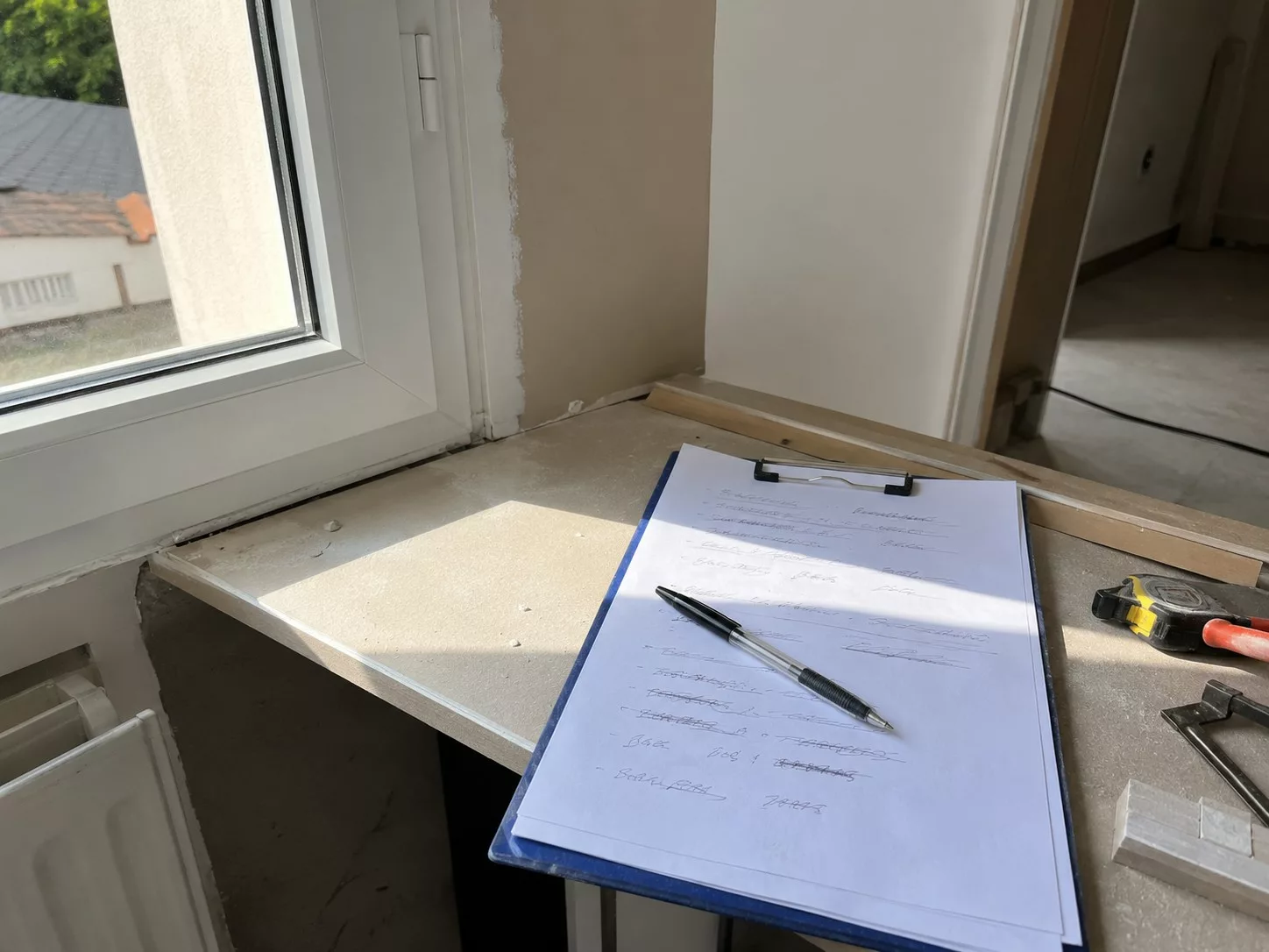 Contrôle d'un défaut de finition de peinture au bord d'une fenêtre lors de la réception des travaux d'une maison, réglette de mesure et rapport de chantier, étape clé du CCMI. Score Expertises, expert bâtiment Paris et Île-de-France.