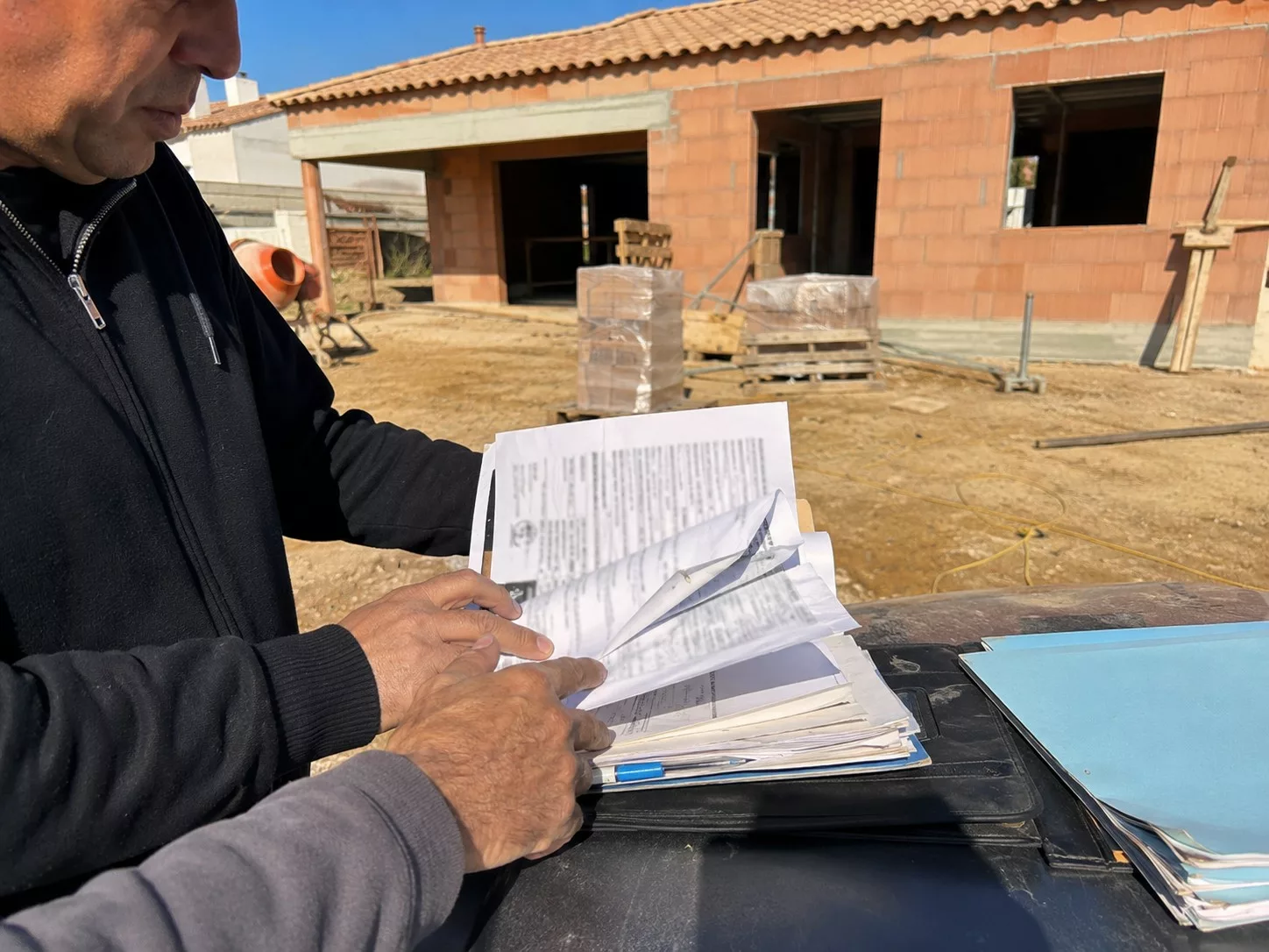 client-et-professionnel-verifiant-contrat-ccmi-clauses-pieges-documents-sur-chantier-maison-individuelle-en-construction-soleil-juillet-2026-format-4-3