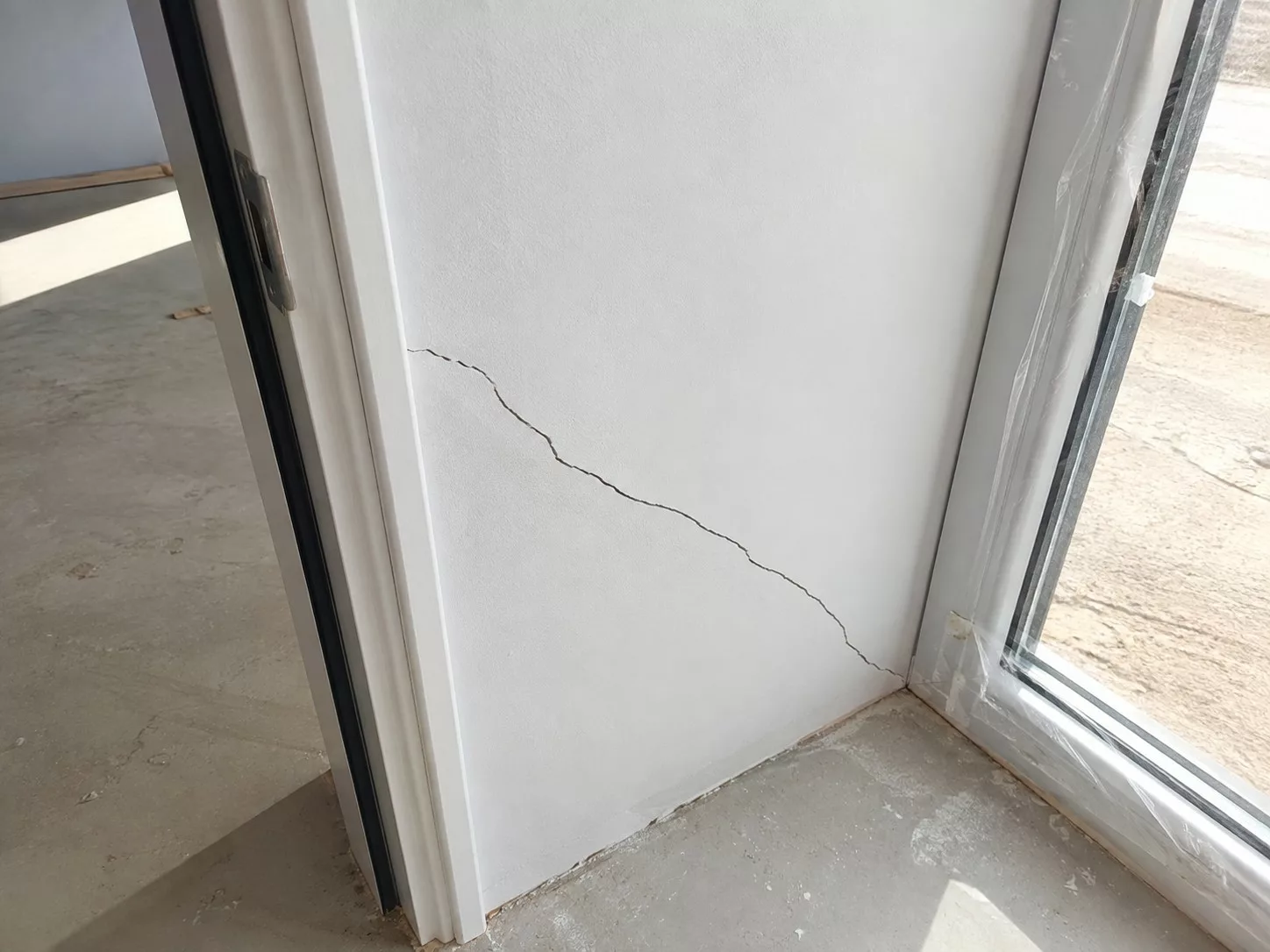 Fissure diagonale sur un mur intérieur près d'un encadrement de porte, dans une maison, contrôle lors d'une expertise bâtiment