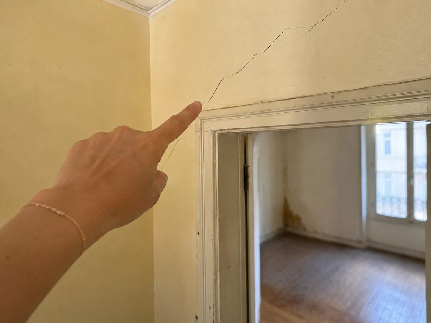 Fissure diagonale au-dessus d’un encadrement de porte observée dans une maison ancienne